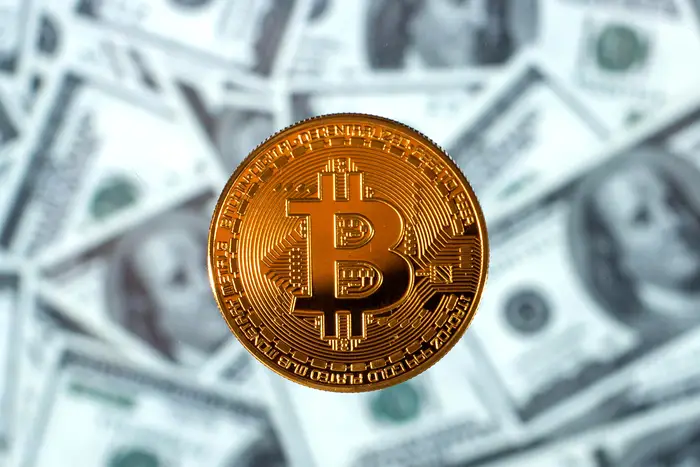 Illustration: Bitcoin on the background of dollar bills.